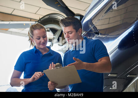 Aero Engineer And Apprentice Working On Helicopter In Hangar Stock Photo