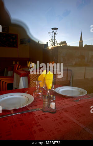 Table for two - Yellow napkins and a red table cloth of a restaurant window Stock Photo