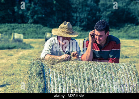 Farmers on hale bale with mobile phone. Ireland Stock Photo
