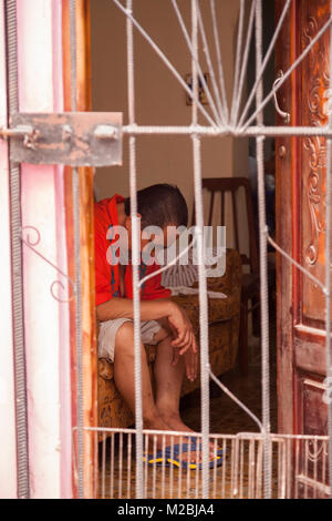 A Cuban man sitting on a couch with his head down in Havana, Cuba. Stock Photo