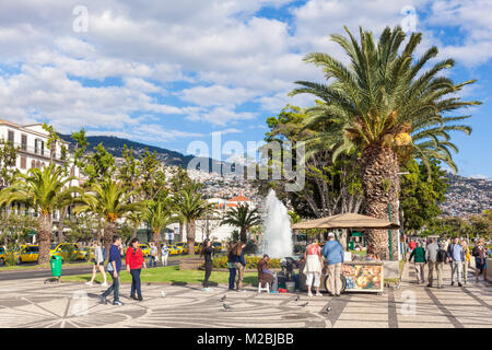 MADEIRA PORTUGAL MADEIRA Funchal tourists wandering past the fountains and a stall selling hot chestnuts on the seafront  Promenade in Funchal madeira Stock Photo