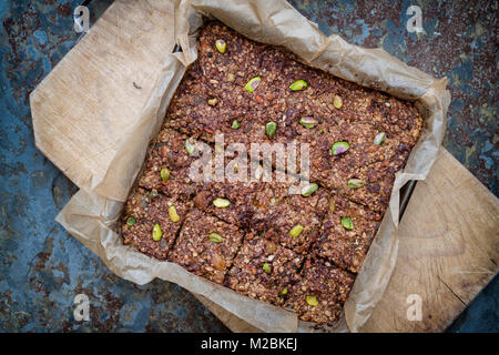 Homemade seed, nut, dried fruit and dark chocolate Oat Energy bars on baking parchment on slate background Stock Photo