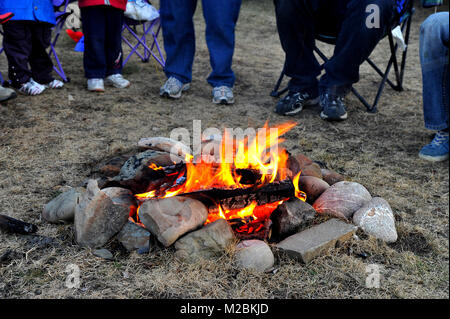 A camp fire in the safety of a stone circle with people gathered around in rural Alberta Canada. Stock Photo