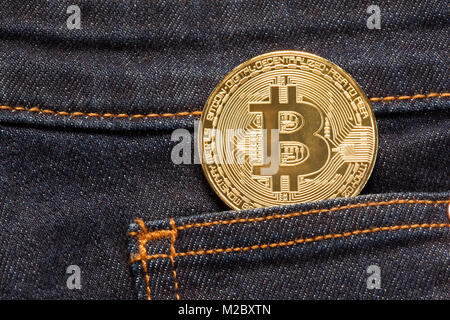 Golden bitcoin physical coin in dark blue denim pocket. Stock Photo
