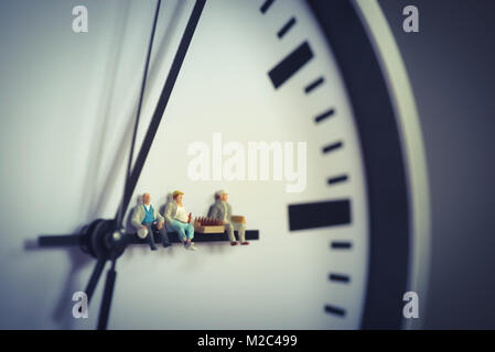 Group of workers having break with beer while sitting on clock hand. Stock Photo