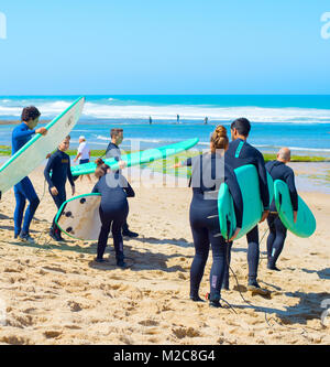 ERICEIRA, PORTUGAL - JUL 23, 2017: Group of surfers with surfboards going to surfing. Ericeira is the famous surfing destination in Portugal. Stock Photo