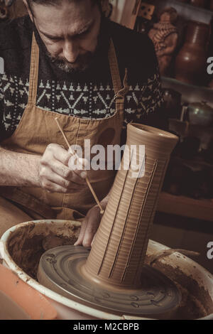 elderly man making pot using pottery wheel in studio Stock Photo