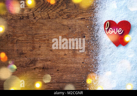 Felt red hearts and wooden inscription 'love' on snow and rustic background. Love and St. Valentines Day concept. Stock Photo