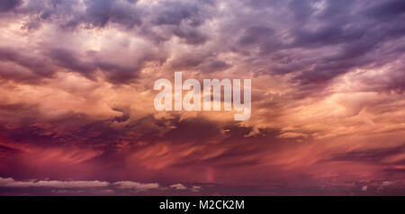 Stormy sky and vertical rainbow over the sea at sunset. Stock Photo
