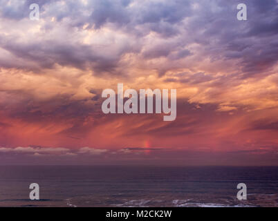 Stormy sky and vertical rainbow over the sea at sunset. Stock Photo