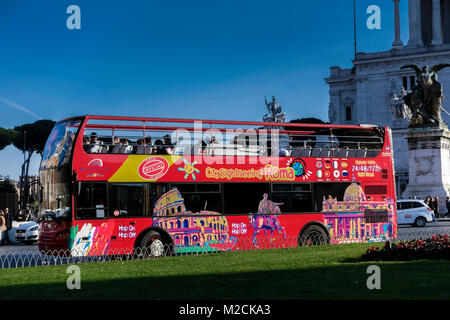 Tourist sightseeing, hop on hop off, red double decker bus, passing through Venice Square. Rome, Italy, Europe, EU. Clear blue sky, copy space. Stock Photo