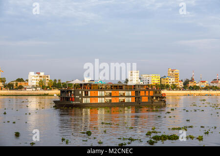 River Boat Aqua Mekong sailing by riverside buildings on the Tone Sap river at Phnom Penh, capital city of Cambodia, south-east Asia Stock Photo