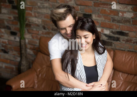 Young millennial couple embracing at home, happy about first pre Stock Photo