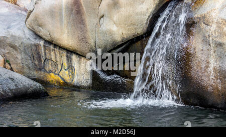 Lovely small waterfall set against beautiful rock background, a hidden spring pond in summer