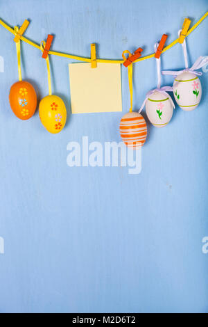 Easter Eggs and paper on a rope on a blue wooden background.  Easter still life can be used as a postcard. Stock Photo