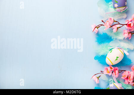 Easter eggs, feathers and flowers on color wooden background. Easter still life with flowers, nest, feathers and eggs. Stock Photo