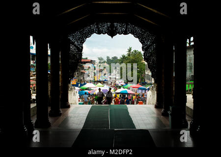 Exiting Shwedagon Pagoda and entering a busy hectic street market, filled with color umbrella stalls. Colorful Yangon, Burma, Myanmar, South East Asia Stock Photo