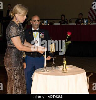 U.S. Army Command Sgt. Maj. Carlos O. Lopes (right) escorts Gold Star Spouse Margaret Good Espaillat (left), widow of Maj. Gen. Francisco A. Espaillat, to the Prisoner of War and Missing Comrades table as she lights a candle during the Maj. Gen. Francisco A. Espaillat Victory Ball conducted at the Rosen Shingle Creek resort in Orlando, Fla., Dec. 16, 2017. The tradition of setting a separate table in honor of American POWs has been in place since the end of the Vietnam War. The manner in which this table is decorated is full of special symbols in honor of those service members separated from t Stock Photo