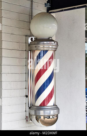 American barber pole on the exterior wall of a small town barber shop in Auburn Alabama, USA. Stock Photo