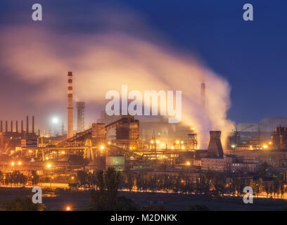 Metallurgical plant at night. Steel factory with smokestacks. Steelworks, iron works. Heavy industry in Europe. Air pollution from smokestacks, ecolog Stock Photo