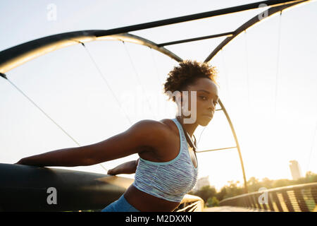 Portrait of mixed race woman stretching arms by pulling on railing Stock Photo