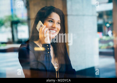 Smiling Hispanic woman talking on cell phone Stock Photo