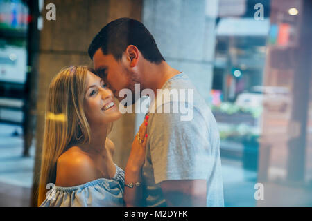 Caucasian man kissing woman on cheek behind window Stock Photo