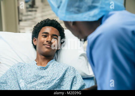 Black doctor talking to boy in hospital bed Stock Photo