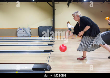 Caucasian woman releasing bowling ball in lane Stock Photo
