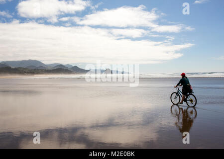 Caucasian woman riding bicycle on beach Stock Photo