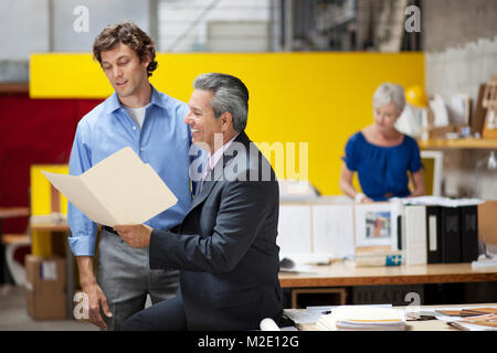 Businessmen reading file folder in office Stock Photo
