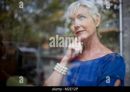 Pensive Caucasian businesswoman looking out window Stock Photo