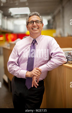 Portrait of smiling Hispanic businessman leaning on desk Stock Photo