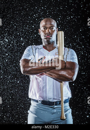 Water splashing on Black baseball player holding bat Stock Photo