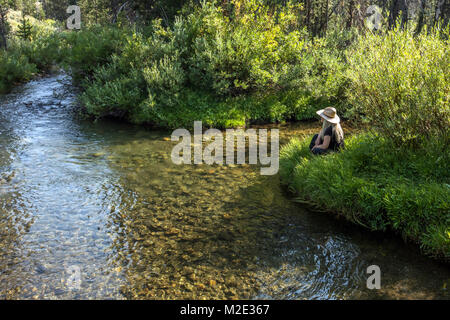 Caucasian woman sitting near tranquil river Stock Photo