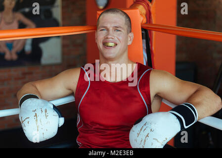 Portrait of Caucasian boxer sitting in corner of boxing ring Stock Photo