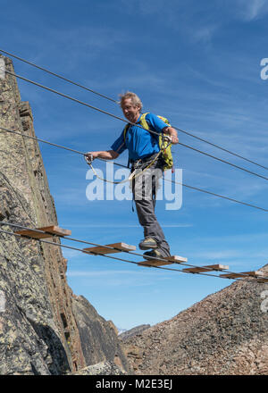 Caucasian man crossing rope bridge on mountain Stock Photo - Alamy