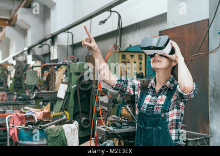 beautiful young industrial factory woman worker using VR technology viewing 3D components design document and using hand touching content in simulatio Stock Photo