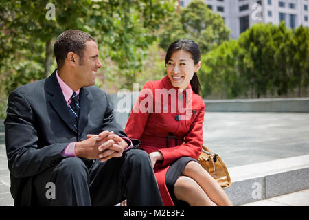 Business people smiling and sitting on staircase outdoors Stock Photo