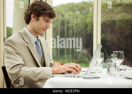 Hispanic businessman using laptop on table at restaurant Stock Photo