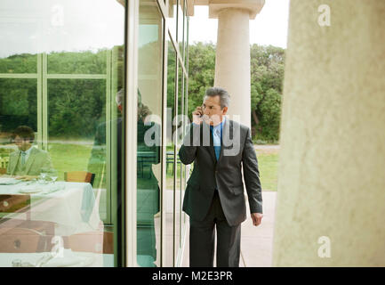 Suspecting Hispanic businessman talking on cell phone Stock Photo