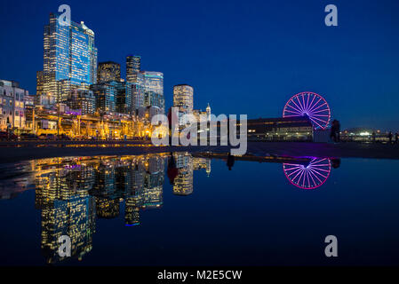 United States, Washington, Seattle, Downtown from waterfront with Big Wheel refectioned in a water puddle Stock Photo