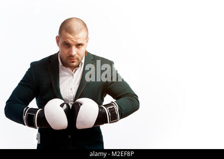 Young bald man, confident business man in white shirt, green suit and boxing gloves looking at camera on white isolated background Stock Photo