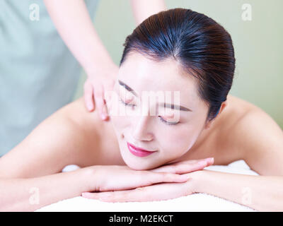 close-up of face of a beautiful young asian woman lying on front on bed receiving massage in spa salon. Stock Photo