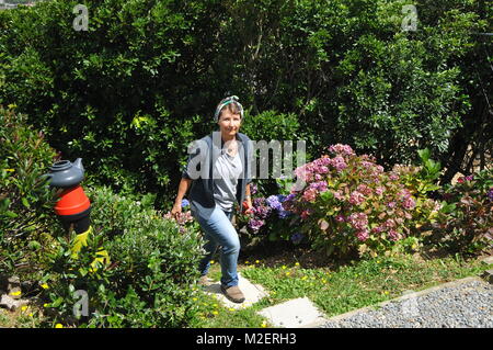 Home gardener walking up a steep site through planted backyard Stock Photo