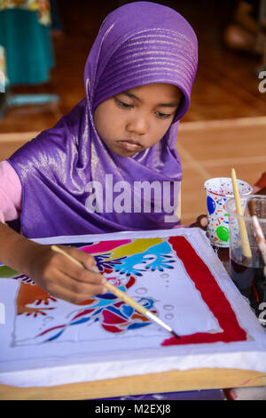 Krabi, Thailand - May 2, 2015: Muslim girl with purple hijab painting Batik fabric in Lanta island of Krabi, Thailand Stock Photo