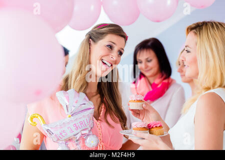 Expecting mother eating cupcake on baby shower party Stock Photo