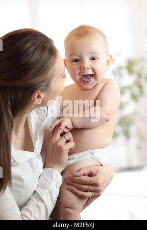Happy family laughing faces, mom holding cute child baby boy. Young woman and her small son have a fun pastime. Stock Photo