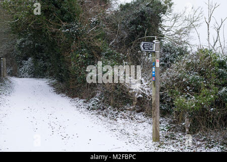 Charing, Kent, UK. 7th Feb, 2018. UK Weather: Specks of snow fell this morning in this part of Kent, very near the Kent downs and the village of Charing. Pictured is a signpost for the north downs way covered in fresh snow and entrance to a pathway. Photo Credit: PAL Images / Alamy Live News Stock Photo