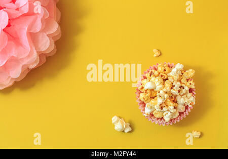 Popcorn on a yellow background. Pink flower.Minimal gallery. Flat lay. Copy space. Stock Photo
